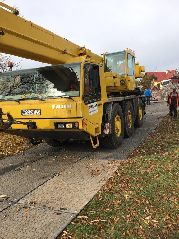 Droga tymczasowa z ciężką maszyną budowlaną zabezpieczająca teren wokół miejsca prac.